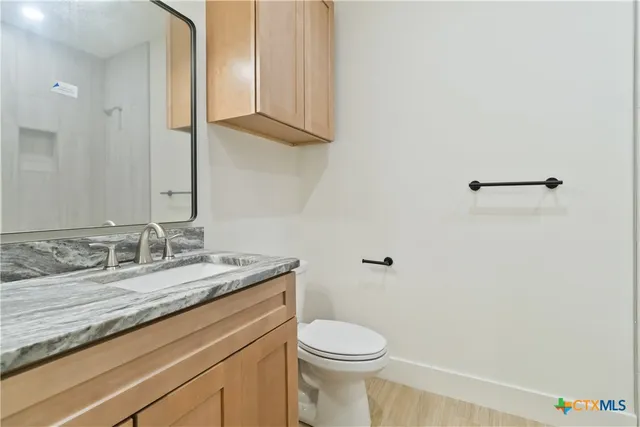 a bathroom with a granite countertop sink a toilet and a mirror