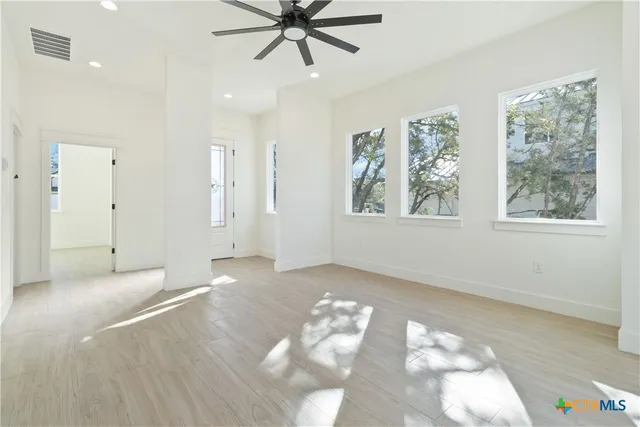 a view of an empty room with a window and wooden floor
