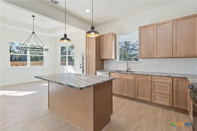 a kitchen with stainless steel appliances granite countertop a sink a stove a refrigerator and island with wooden floor