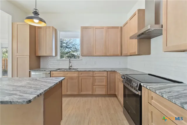 a kitchen with granite countertop a sink a counter top space and cabinets