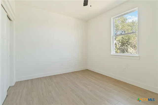 a view of empty room with wooden floor and fan