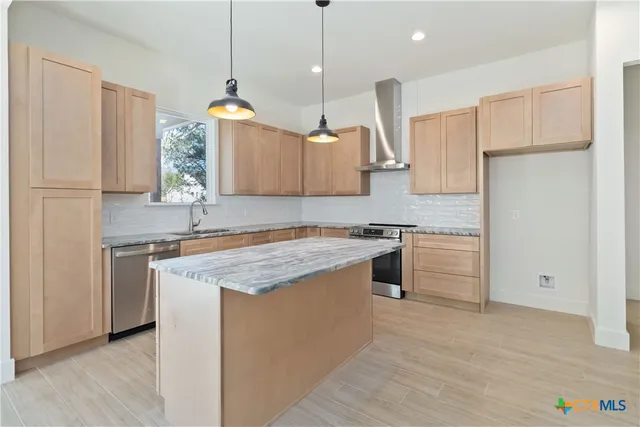 a view of a kitchen with stainless steel appliances granite countertop a stove top oven a sink a counter space and cabinets