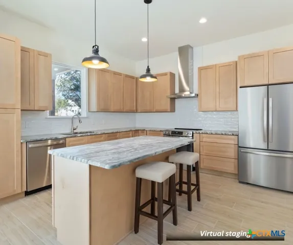 a kitchen with stainless steel appliances granite countertop a stove a sink a refrigerator a center island with wooden floor and cabinets