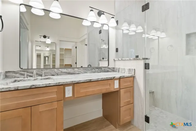 a bathroom with a granite countertop sink a large mirror and a shower
