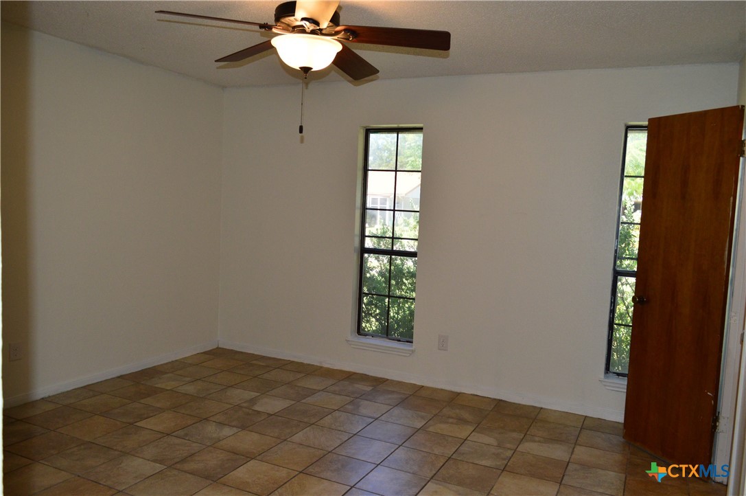 1404 Rob Lane Copperas Cove, TX 76522 - Photo 19 of 31 an empty room with windows and chandelier fan