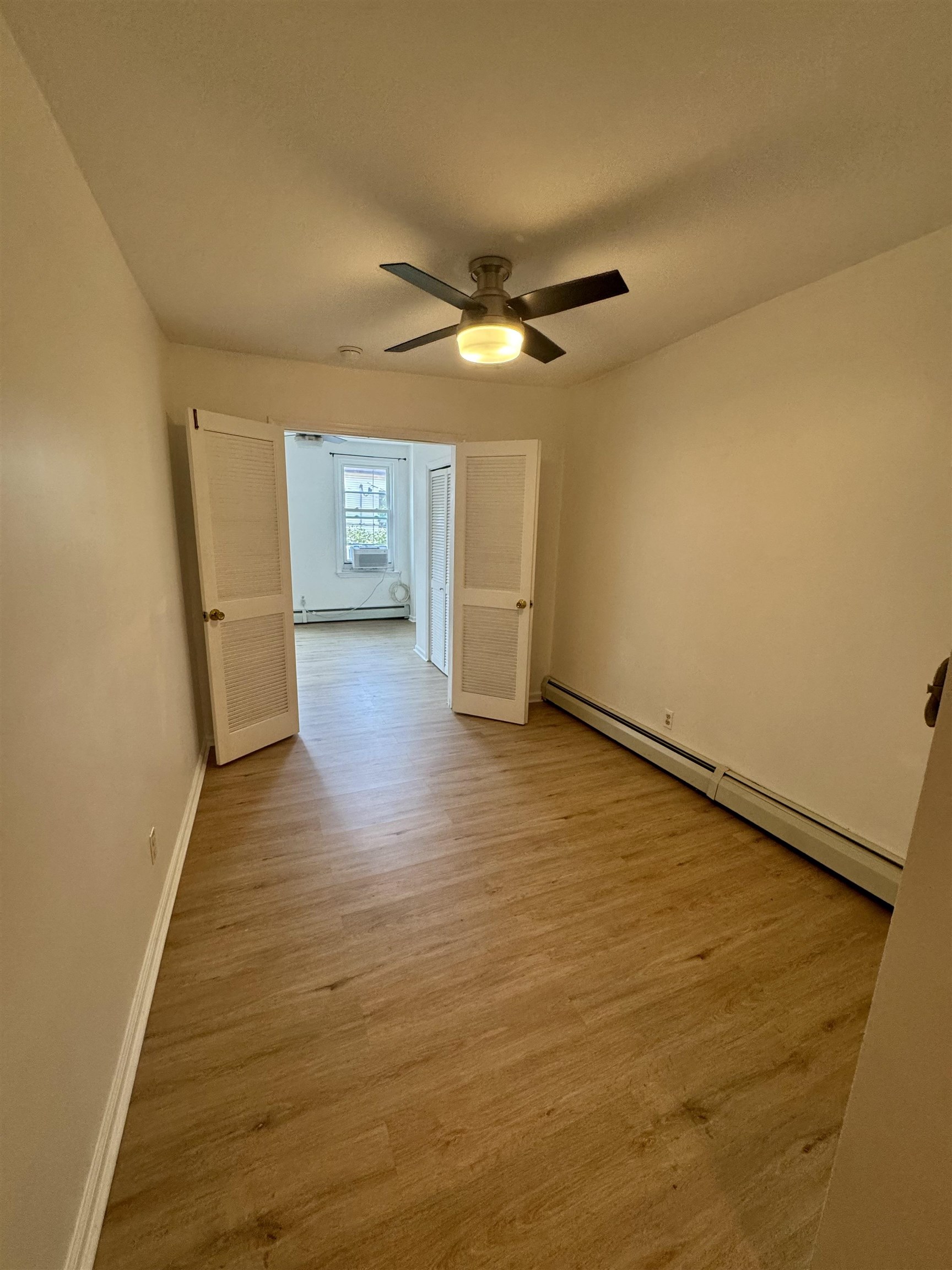 421 Adams Street, Unit 2L Hoboken, NJ 07030 - Photo 8 of 19 a view of a big room with wooden floor a ceiling fan and windows