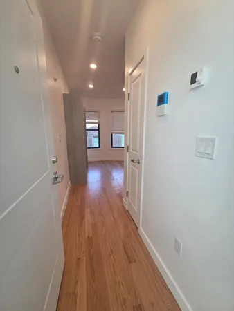 a view of a hallway with wooden floor and a refrigerator