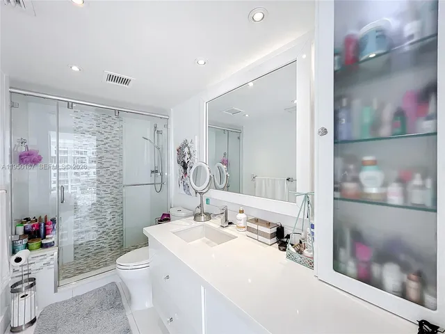 a bathroom with a sink vanity granite toilet and shower