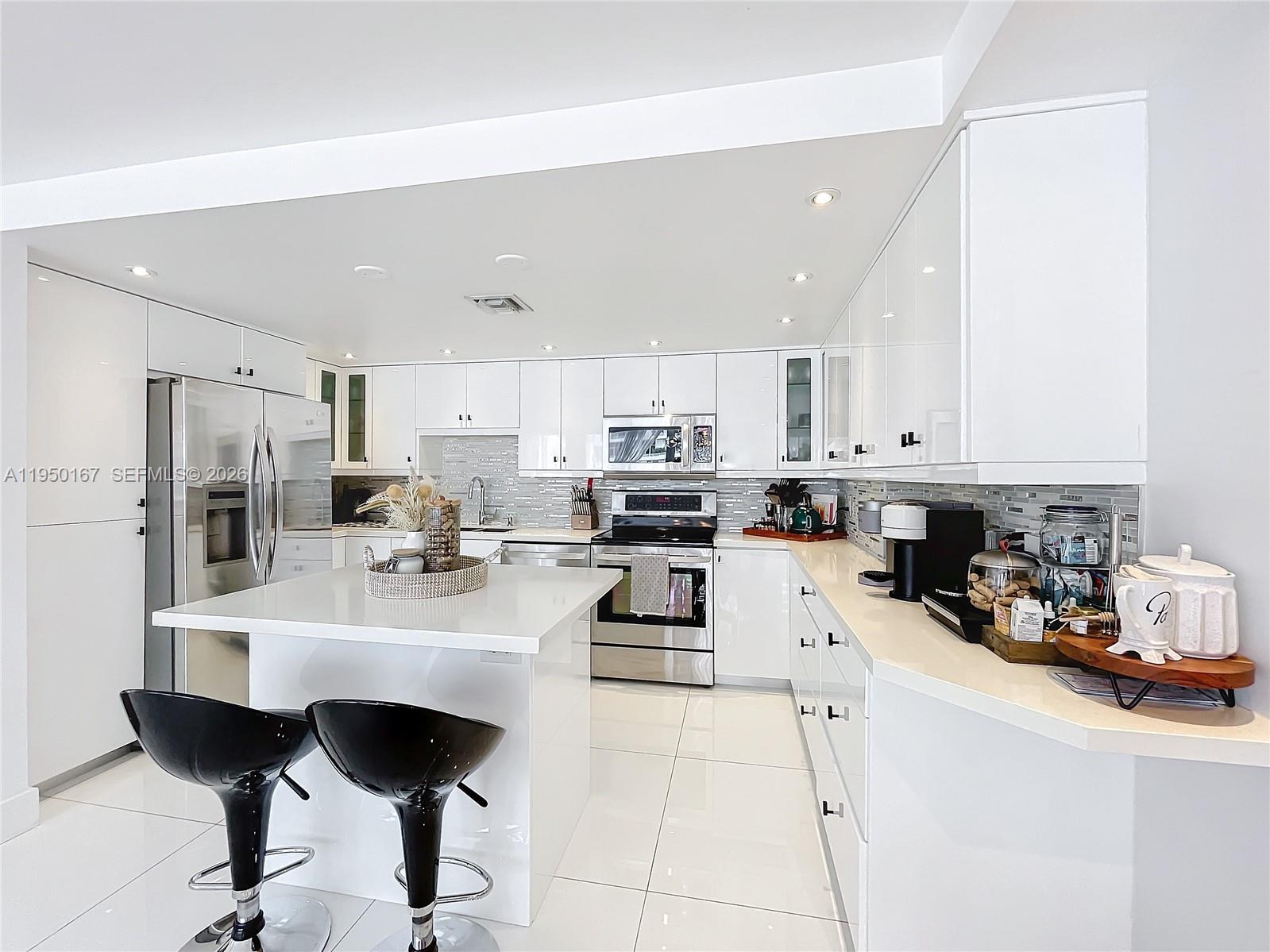 600 Northeast 36th Street, Unit 703 Miami, FL 33137 - Photo 7 of 48 a kitchen with stainless steel appliances kitchen island granite countertop a sink a stove a refrigerator and white cabinets with wooden floor