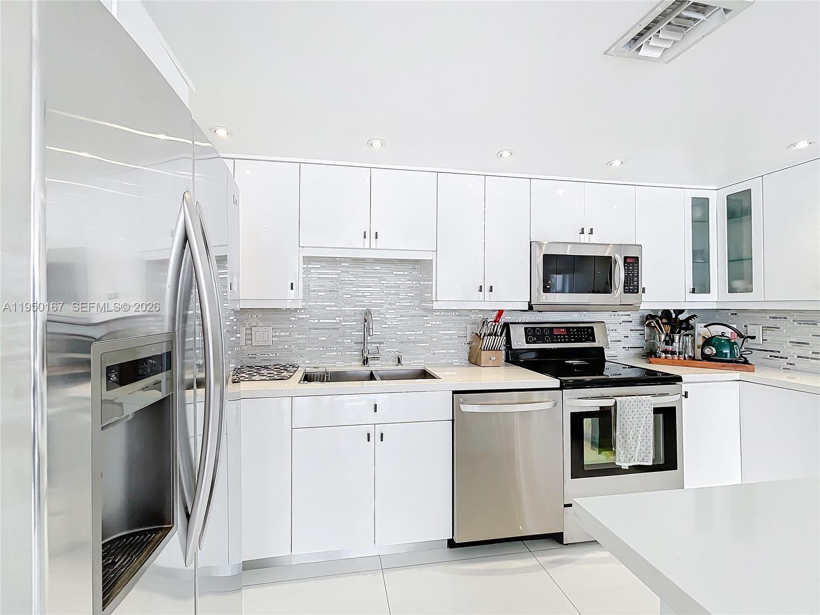600 Northeast 36th Street, Unit 703 Miami, FL 33137 - Photo 10 of 48 a kitchen with white cabinets stainless steel appliances and sink