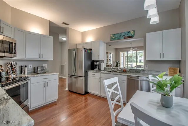 a kitchen with a refrigerator a stove a sink dishwasher a dining table and chairs with wooden floor