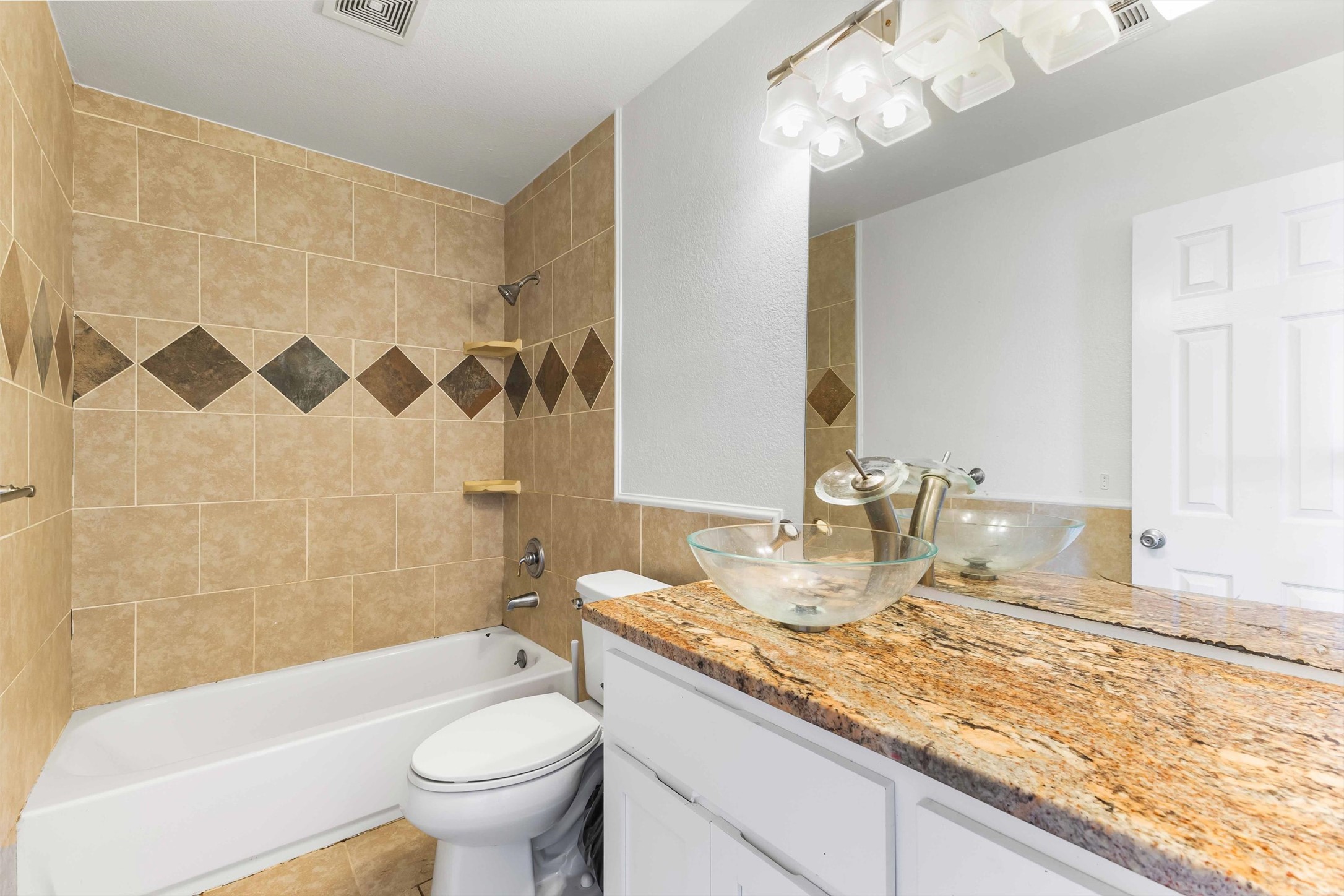 12212 Ballerstedt Road Elgin, TX 78621 - Photo 25 of 39 a bathroom with a granite countertop sink a toilet a mirror a bathtub and shower