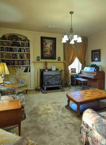 190 North 200 E Street Beaver, UT 84713 - Photo 19 of 40 Living area with built-in arched shelving, an ornate chandelier, a traditional wood-burning stove on a brick hearth, and a window with drapery