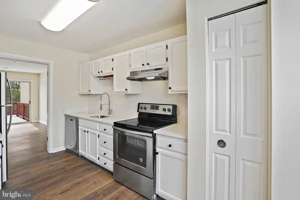 a kitchen with stainless steel appliances granite countertop white cabinets and window