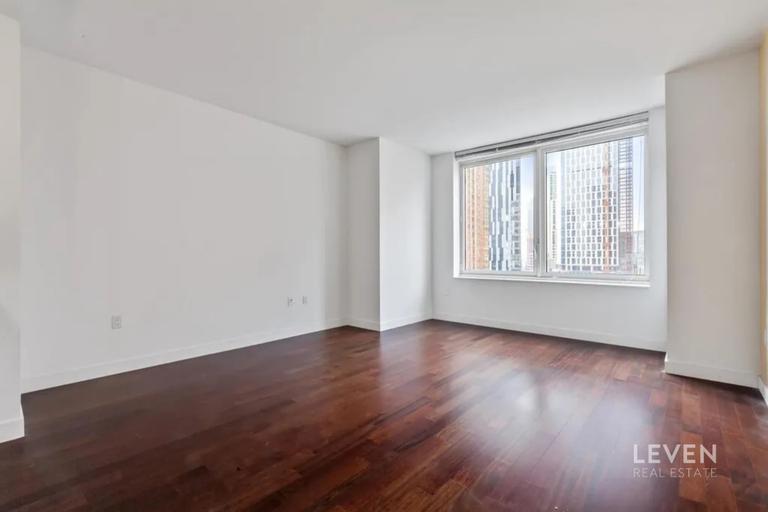 306 Gold Street, Unit 16D Brooklyn, NY 11201 - Photo 2 of 15 a view of an empty room with wooden floor and a window