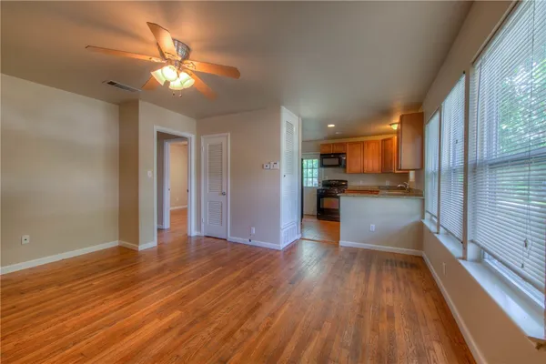 a view of a hallway with wooden floor and a kitchen