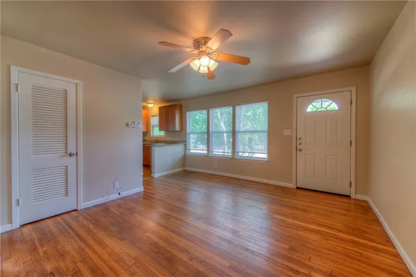 a view of an empty room with window and wooden floor
