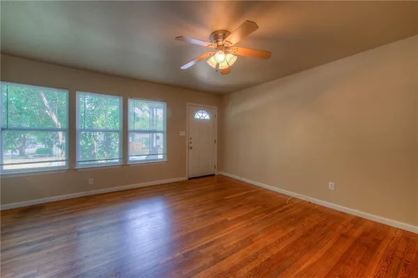a view of an empty room with wooden floor and a window