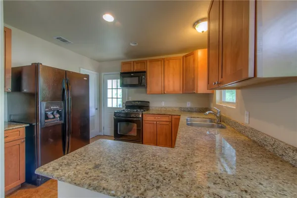 a kitchen with stainless steel appliances granite countertop a refrigerator sink and stove