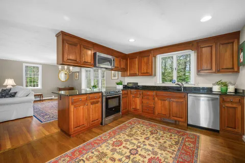 a kitchen with stainless steel appliances granite countertop a stove a sink dishwasher and a microwave oven with white cabinets