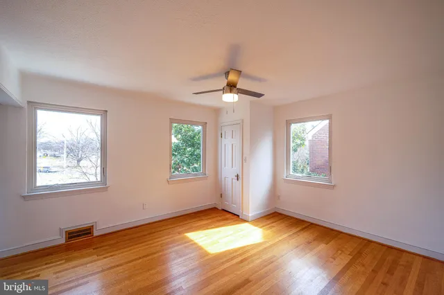 a view of an empty room with a window and wooden floor
