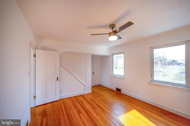 a view of empty room with wooden floor and fan