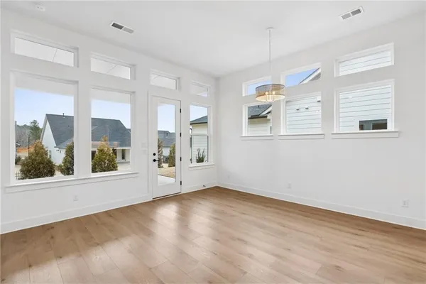 an empty room with wooden floor and windows