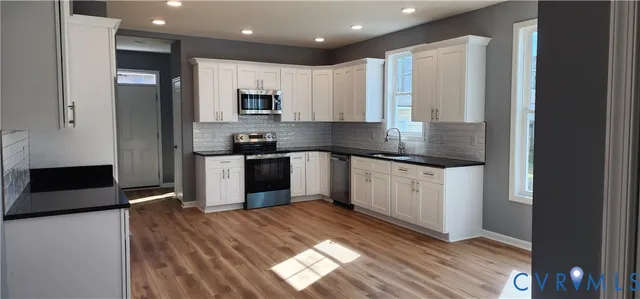 a kitchen with stainless steel appliances granite countertop a stove a sink and a refrigerator