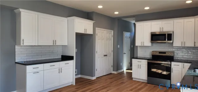 a kitchen with granite countertop white cabinets and stainless steel appliances