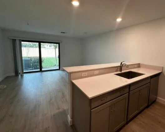 a kitchen with a sink a large window and wooden floor