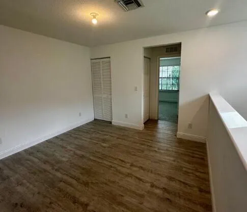 an empty room with wooden floor and windows