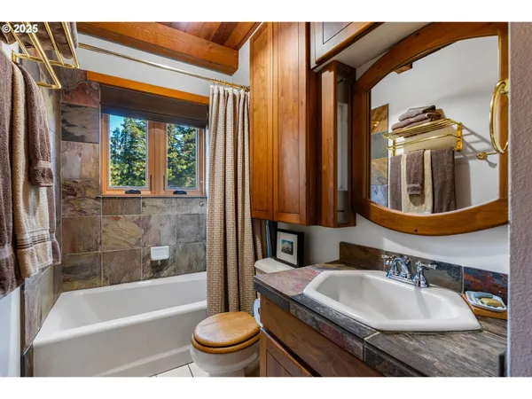 a bathroom with a granite countertop sink a toilet a mirror and bathtub