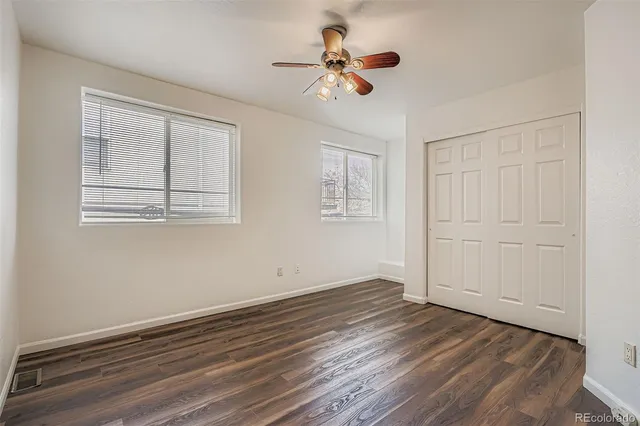 a view of empty room with wooden floor and fan