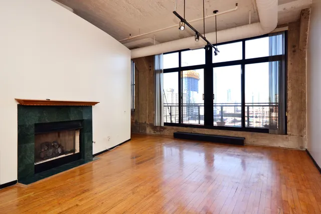 a view of an empty room with wooden floor and a fireplace