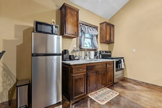 a kitchen with stainless steel appliances granite countertop a refrigerator a sink and a stove