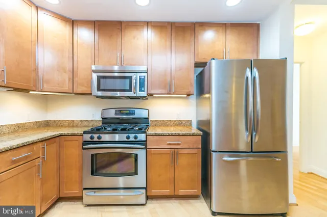 a kitchen with stainless steel appliances granite countertop a sink and a refrigerator