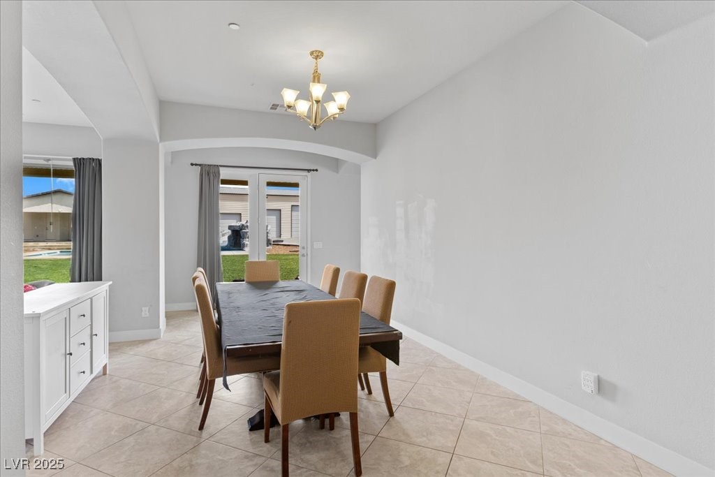 259 Milan Street Henderson, NV 89015 - Photo 11 of 99 Dining area featuring light tile patterned floors, a chandelier, and arched walkways