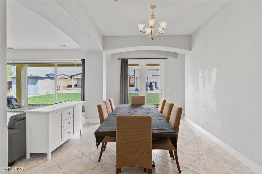 259 Milan Street Henderson, NV 89015 - Photo 12 of 99 Dining area featuring arched walkways, light tile patterned flooring, and a chandelier