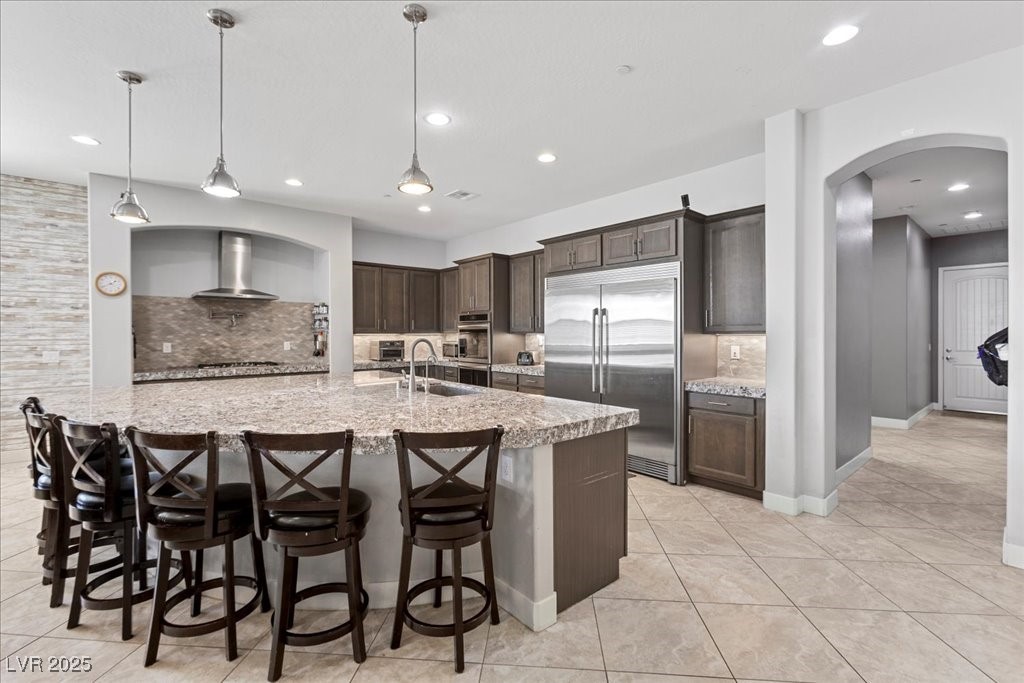 259 Milan Street Henderson, NV 89015 - Photo 24 of 99 Kitchen featuring dark brown cabinetry, appliances with stainless steel finishes, tasteful backsplash, arched walkways, and recessed lighting