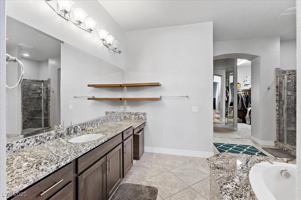 259 Milan Street Henderson, NV 89015 - Photo 32 of 99 Bathroom with vanity, a stall shower, a spacious closet, a garden tub, and light tile patterned floors