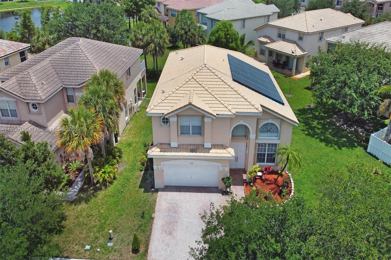 a aerial view of a house with yard and trees in the background