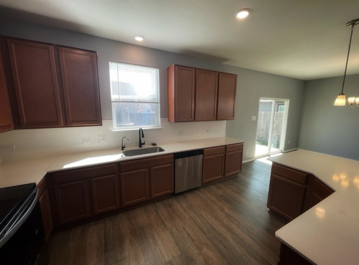 13905 Inaugural Street Manor, TX 78653 - Photo 11 of 26 Kitchen with electric range, light countertops, dark wood finished floors, stainless steel dishwasher, and pendant lighting