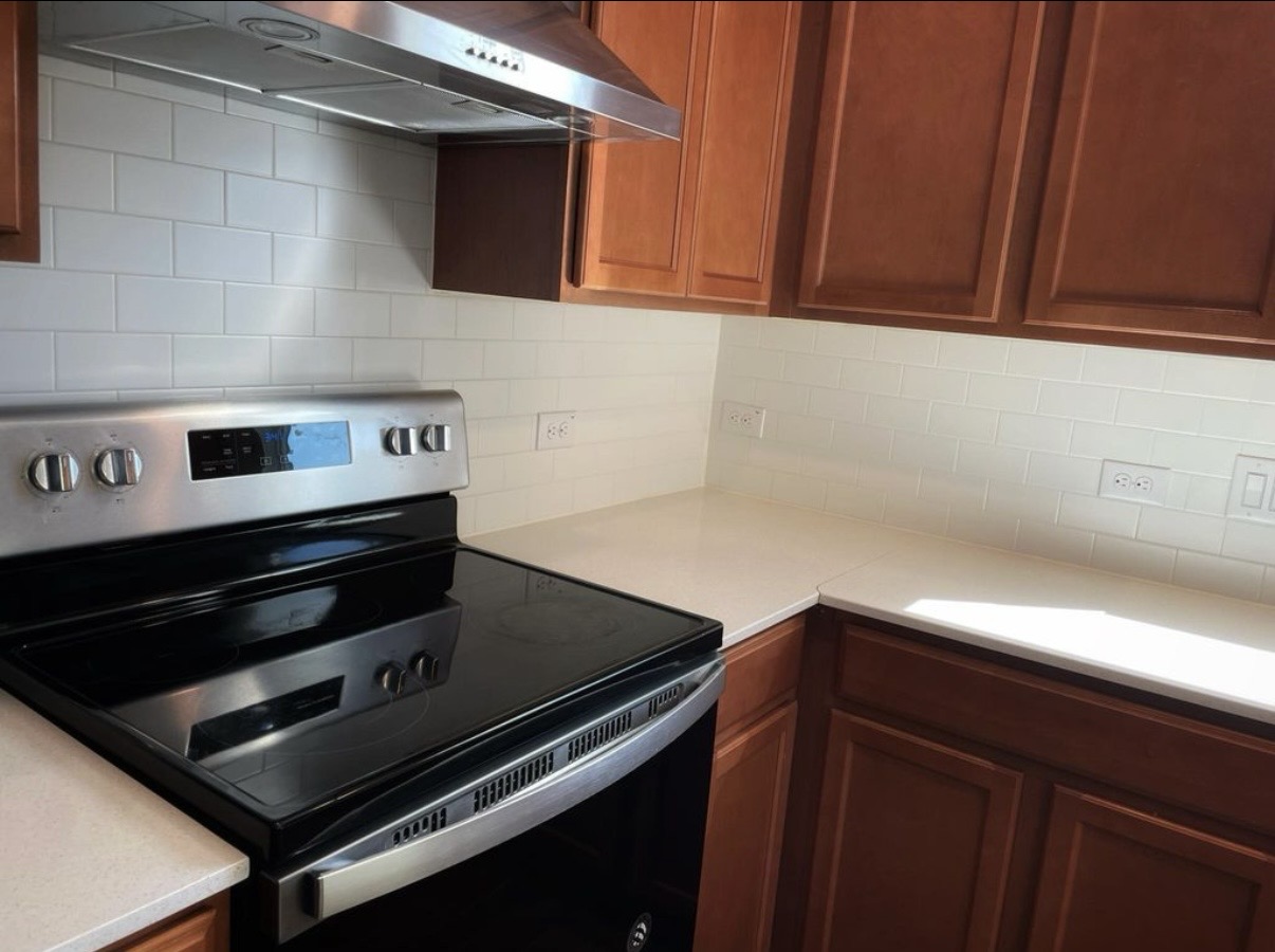 13905 Inaugural Street Manor, TX 78653 - Photo 12 of 26 Kitchen with electric range, ventilation hood, wood finish cabinetry, and backsplash