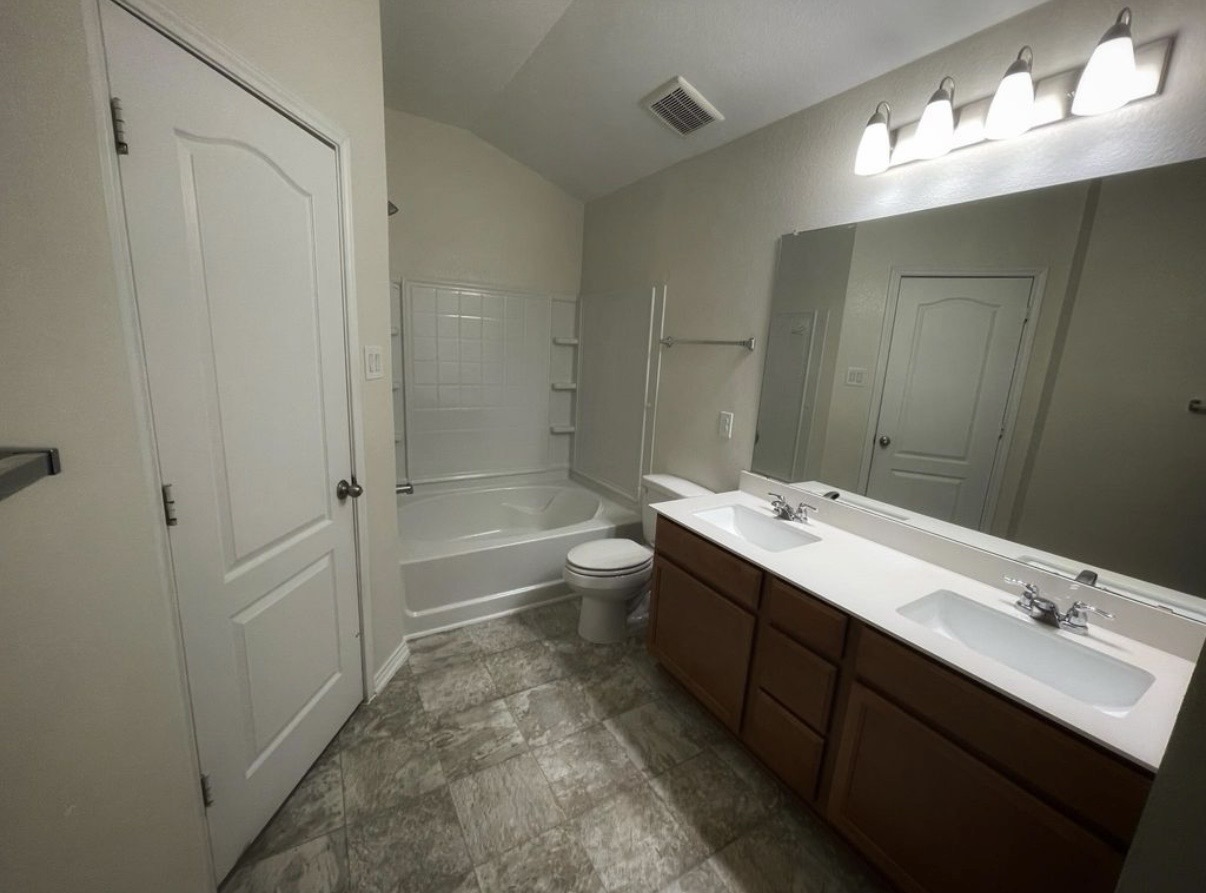 13905 Inaugural Street Manor, TX 78653 - Photo 16 of 26 Bathroom featuring double vanity, shower combination, and lofted ceiling