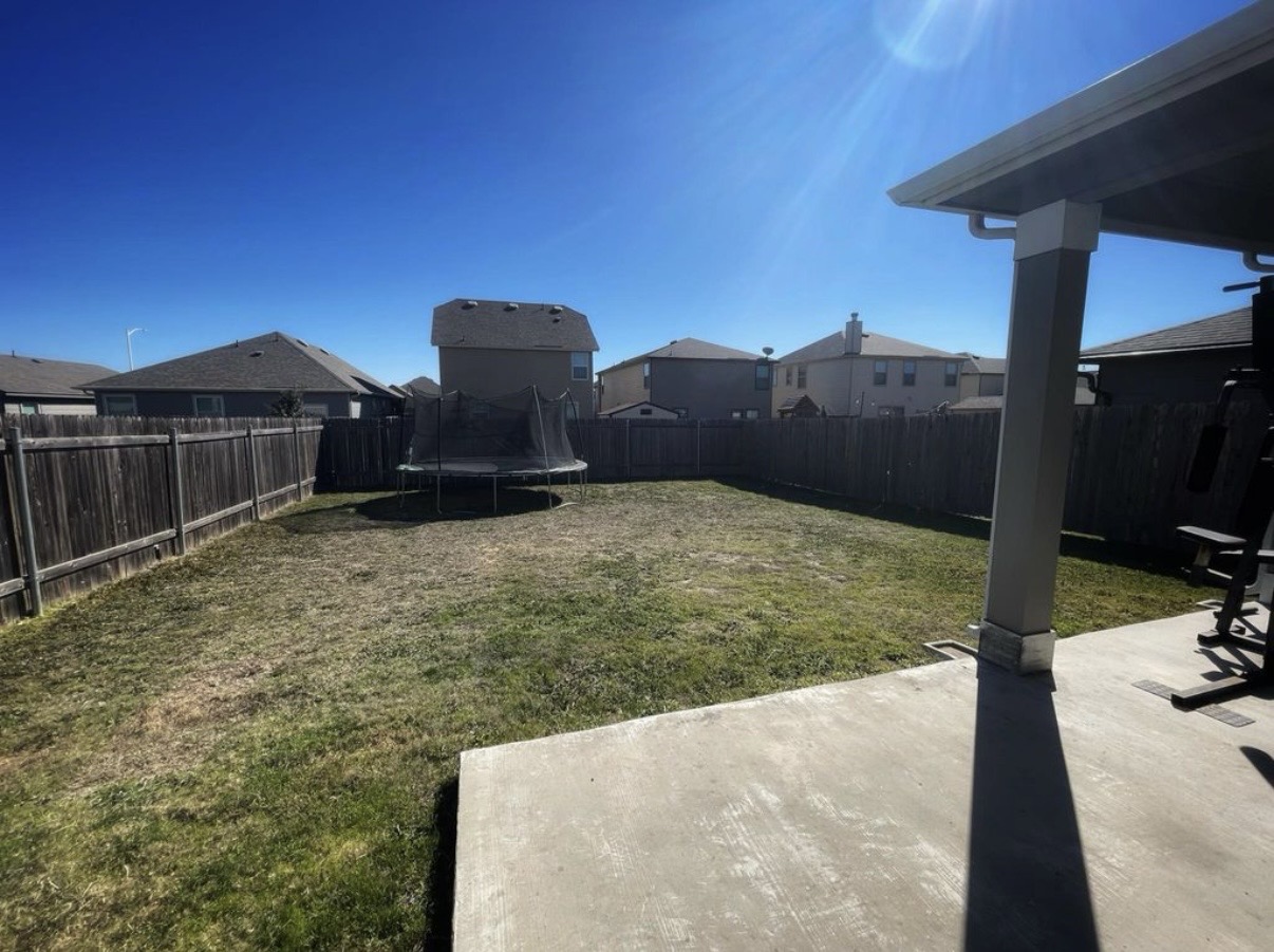 13905 Inaugural Street Manor, TX 78653 - Photo 22 of 26 Fenced backyard with a trampoline, a patio area, and a residential view