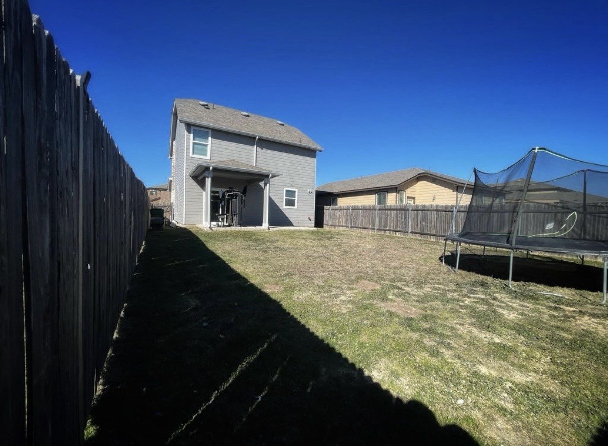13905 Inaugural Street Manor, TX 78653 - Photo 23 of 26 Back of property featuring a patio area, a fenced backyard, and a trampoline