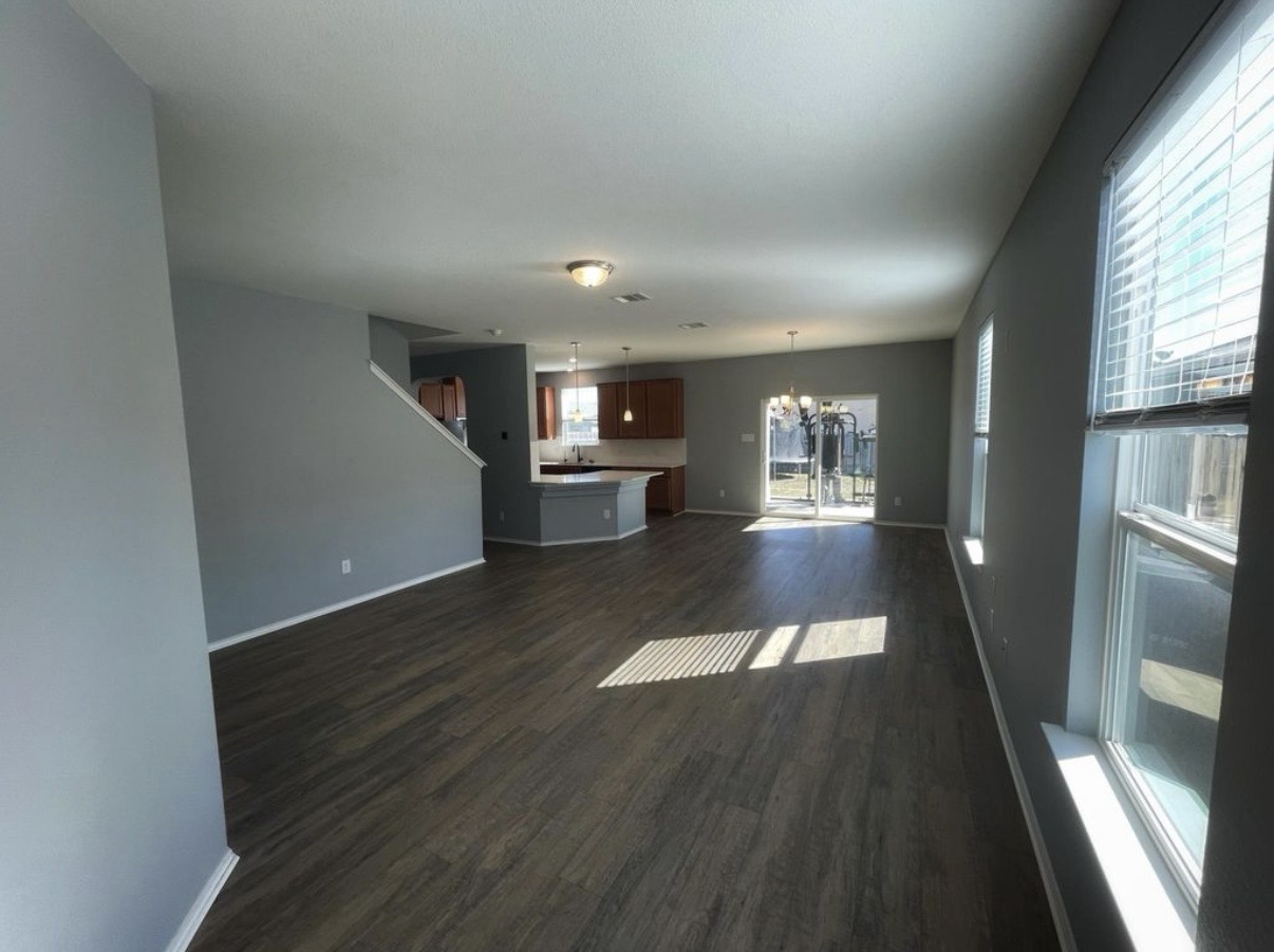 13905 Inaugural Street Manor, TX 78653 - Photo 4 of 26 Unfurnished living room with hanging lights and dark wood-style flooring