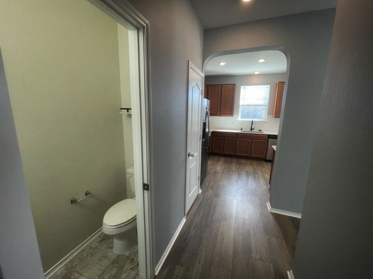 13905 Inaugural Street Manor, TX 78653 - Photo 10 of 26 Hall featuring arched walkways, a textured wall, dark wood-style flooring, and recessed lighting