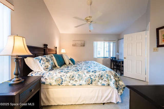 a bed sitting in a bedroom next to a window with pc on the table and a window