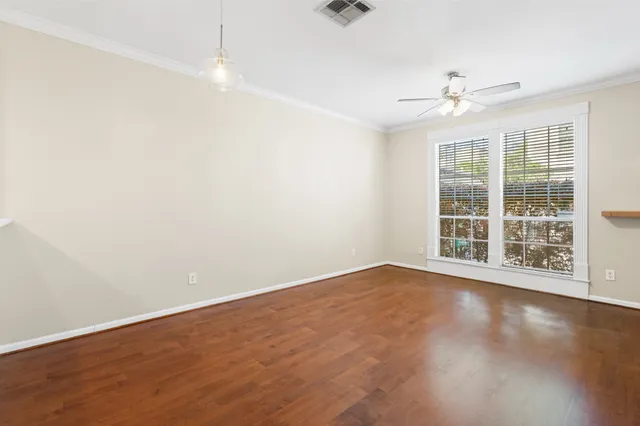 an empty room with wooden floor fan and windows
